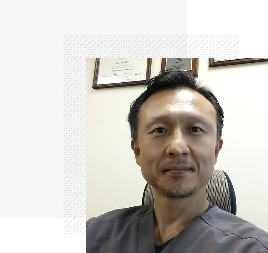 A man in grey shirt sitting at desk.