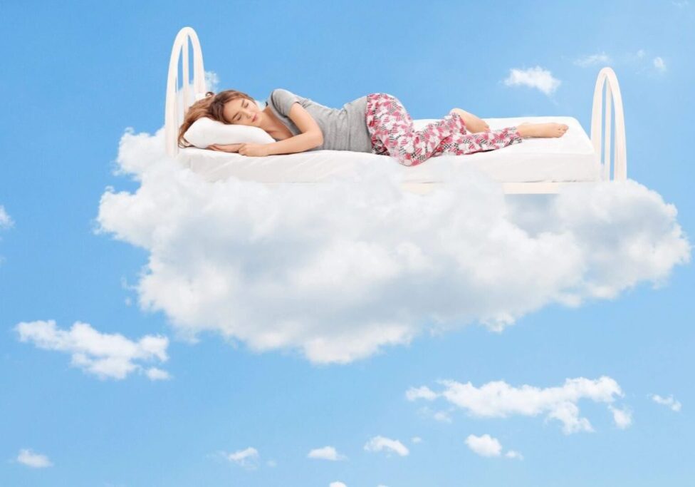A woman laying on top of a cloud in the sky.